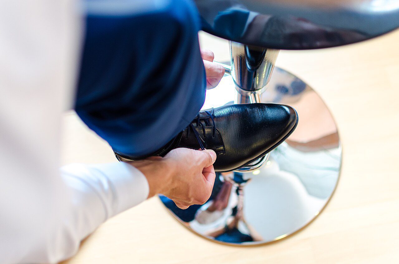 Business man is putting on elegant shoes Unsplash - Top Chaussures homme et femme au Maroc